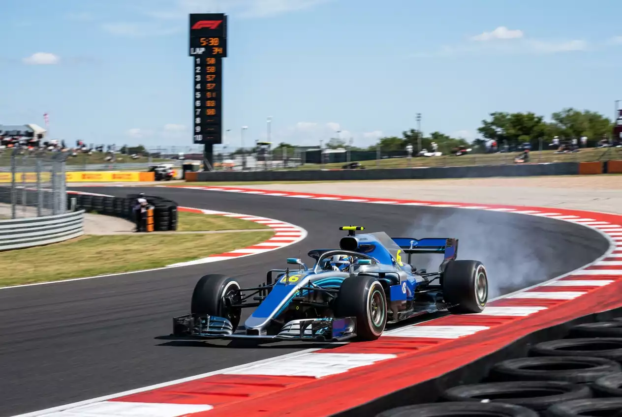 Formula 1 car at full speed through a corner with a timing tower displaying lap times beside the track